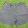 Man wearing charcoal grey casual men's shorts with front pockets and a black t-shirt, standing against a white background.