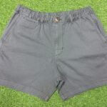 Man wearing charcoal grey casual men's shorts with front pockets and a black t-shirt, standing against a white background.