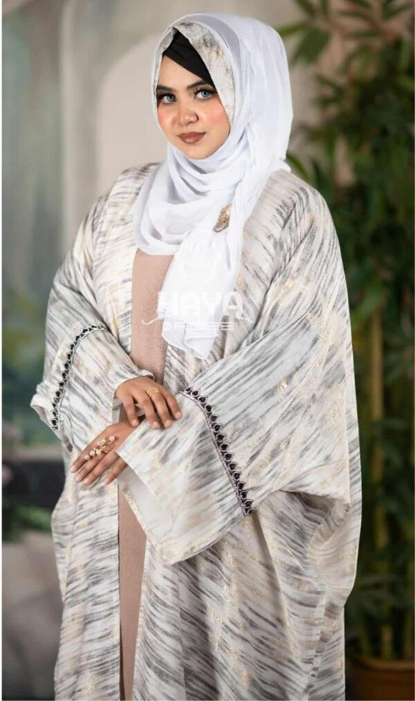 Woman wearing a Simar Lace Parsha Abaya in a soft gray pattern with elegant black lace details, styled with a white hijab.