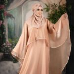 Armani Silk Stylish Abaya. Woman wearing an elegant peach Armani silk abaya with flowy sleeves and matching hijab.