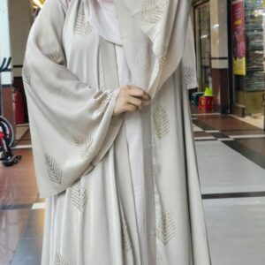 Woman wearing a luxurious Armani Silk Farasha Abaya with embroidered leaf patterns in a shopping mall.