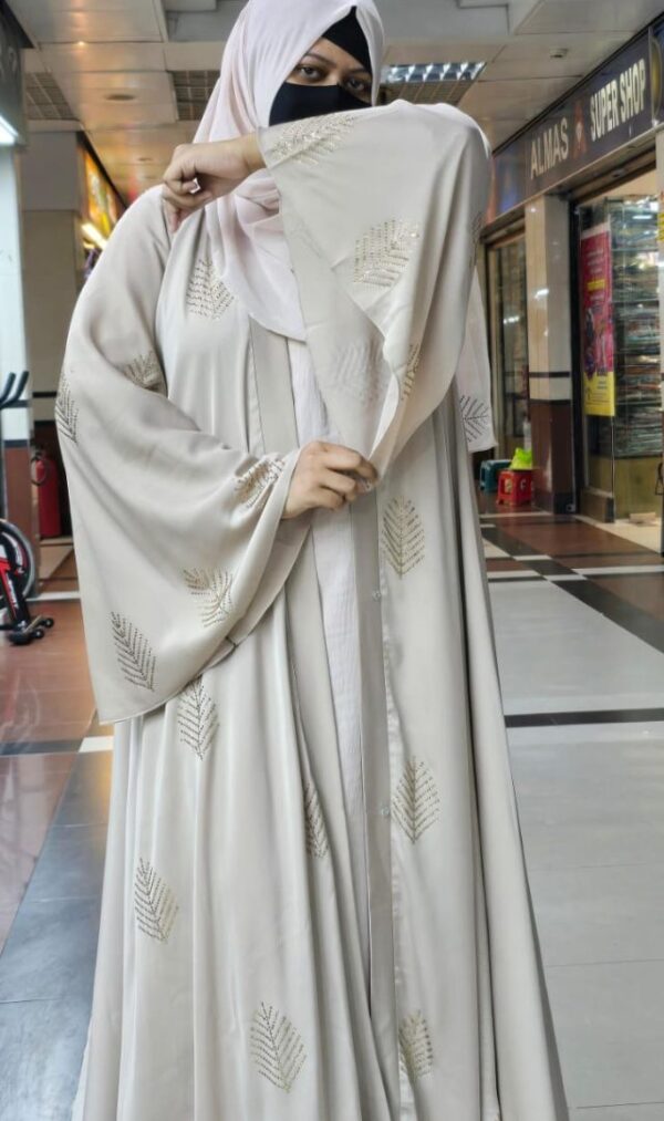 Woman wearing a luxurious Armani Silk Farasha Abaya with embroidered leaf patterns in a shopping mall.