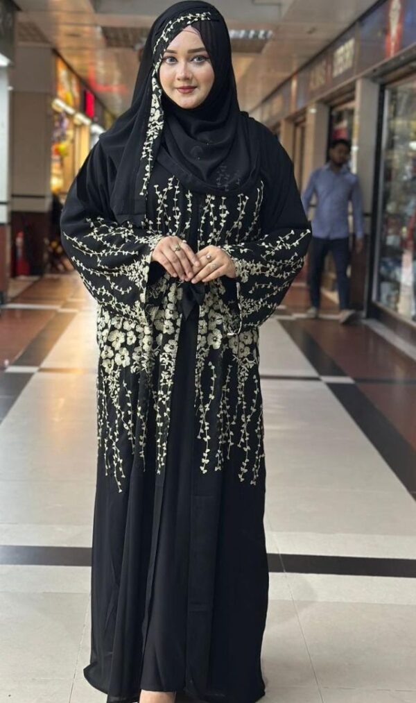 Woman wearing a black Dubai imported original borka with intricate golden floral embroidery.